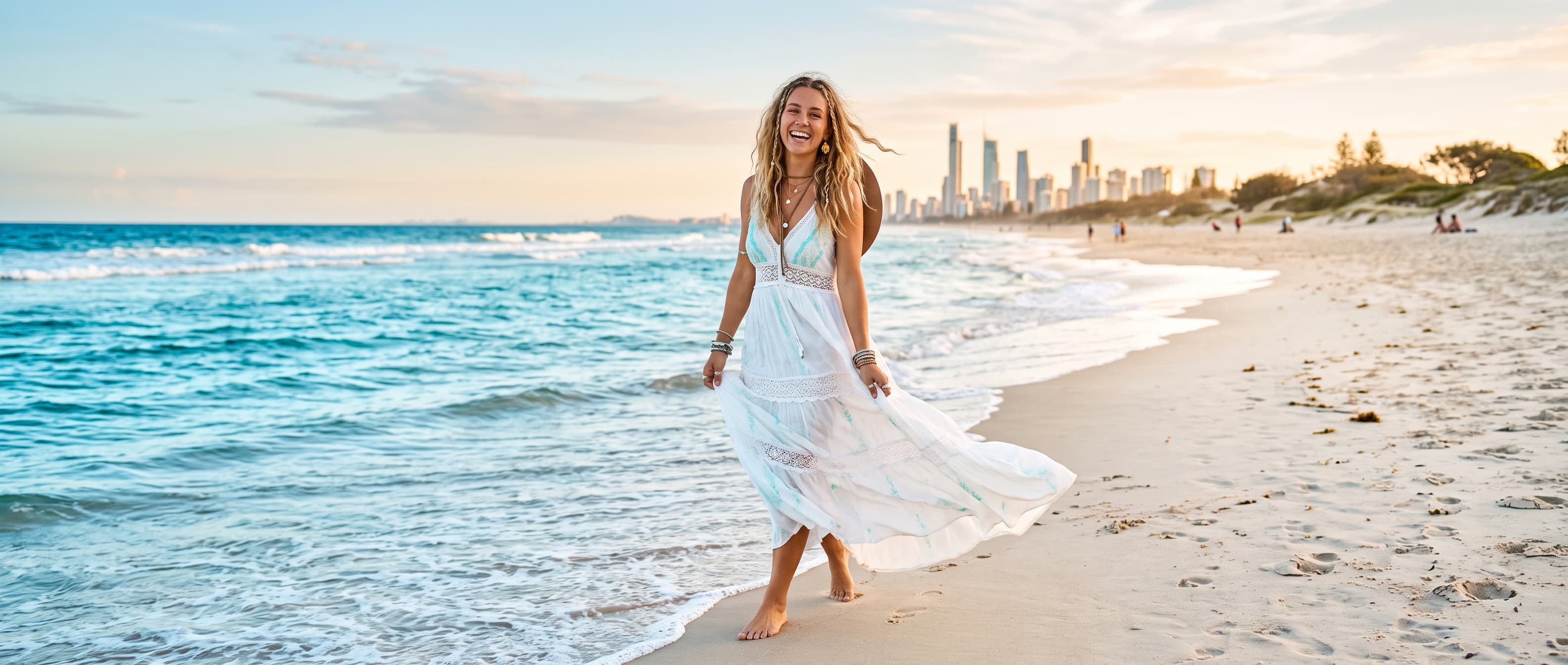 Woman in a white boho maxi dress walking along the shoreline at golden hour